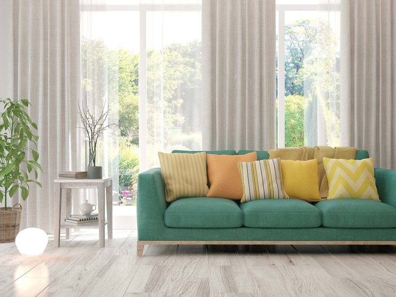 green couch with colourful cushions on tile floor